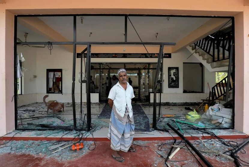 Seorang Muslim berdiri di depan tokonya yang dihancutkan massa pada 2021. (Dinuka Liyanawatte/Reuters) 