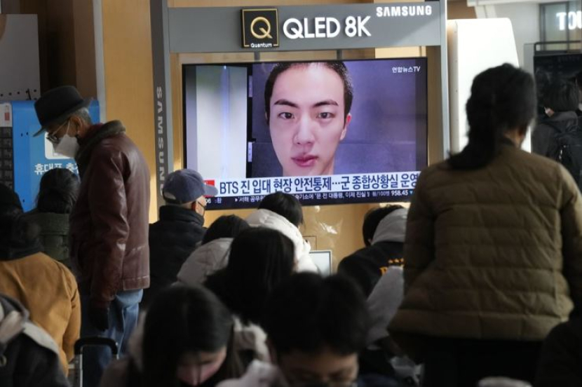 Layar TV menampilkan gambar anggota BTS Jin di Stasiun Kereta Api Seoul di Seoul, Korea, Senin (12/12/2022). Foto:  AP-Yonhap