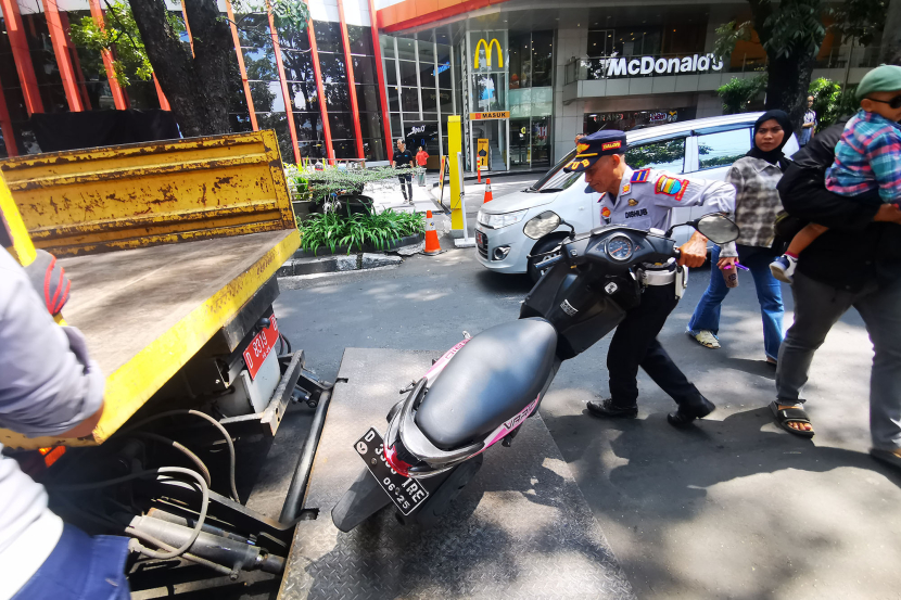 Petugas Dinas Perhubungan menaikkan sepeda motor yang terparkir di badan jalan Jl Purnawarman Bandung, Senin (15/7/2024). (Foto: Yogi Ardhi/KangJepret)