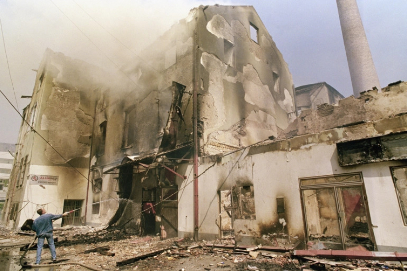 Dalam foto dari 15 Mei 1992, seorang sukarelawan lokal menyiram gedung yang terbakar di Sarajevo, setelah dihancurkan oleh serangan artileri berat pasukan Serbia[File: AP Photo/Santiago Lyon]