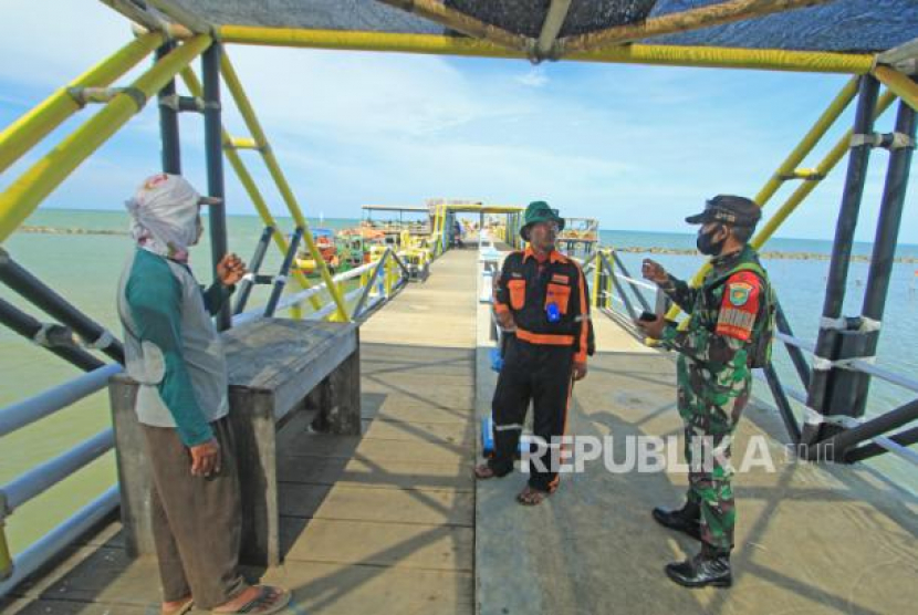 Personel TNI dan Polri mengimbau wisatawan untuk menerapkan protokol kesehatan di objek wisata Pantai Tirtamaya, Indramayu, Jawa Barat. (Dedhez Anggara/ANTARA)