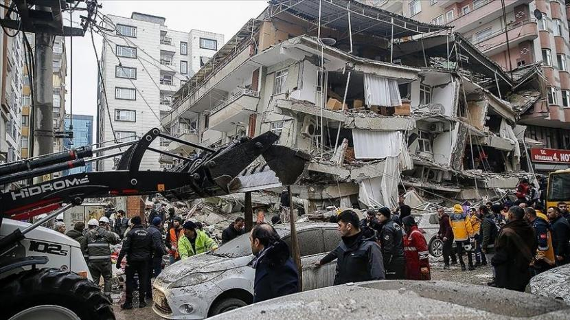 Seorang pria mencari korban gempa di puing-puing bangunan yang hancur di Gaziantep, Turki, Senin (6/2/2023). Gempa kuat telah merobohkan beberapa bangunan di tenggara Turki dan Suriah dan dikhawatirkan banyak korban jiwa. Foto: AP Photo/Mustafa Karali