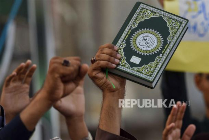  Demonstran mengangkat tangan dan mengangkat Alquran saat mereka menghadiri protes menentang pembakarannya di Swedia, di Karachi, Pakistan, Ahad (2/7/2023). Sikapi Pembakaran Alquran dengan Elegan, Ini yang Dilakukan Pemain Bola Muslim dan Fan di Irak. Foto: EPA/ SHAHZAIB AKBER