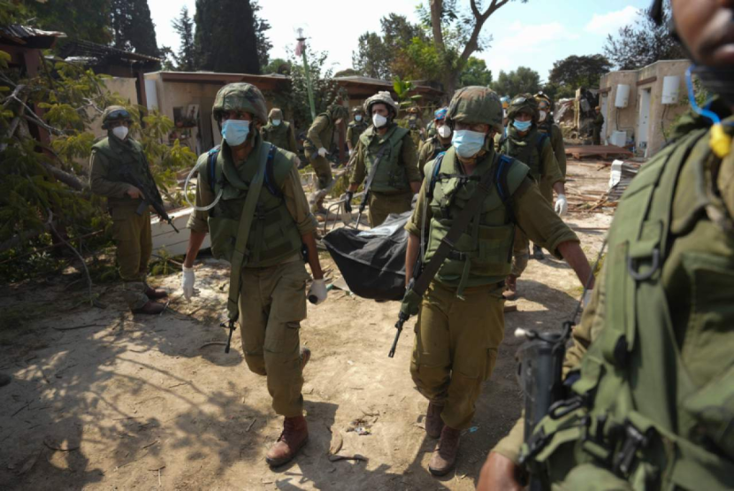 Tentara Israel membawa jenazah seseorang yang tewas dalam serangan Hamas di kibbutz Kfar Azza pada Selasa, 10 Oktober 2023. | AP Photo/Erik Marmo