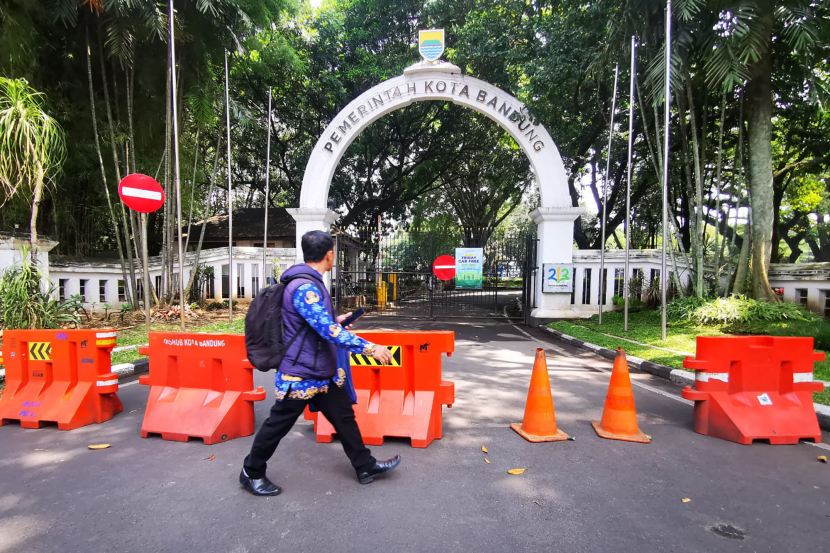 Seorang Apara Sipil Negara Pemkot Bandung melintasi gerbang Balai Kota yang ditutup bagi kendaraan selama Friday Car Free Day di Kompleks Balai Kota Bandung, Jumat (17/5/2024) (Foto: Yogi Ardhi/Republika Network)
