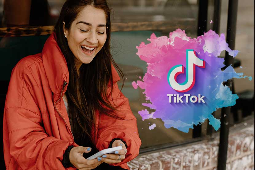 Wanita tertawa melihat aplikasi Tiktok di HP-nya.