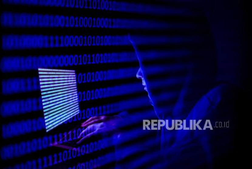  Seseorang yang berpakaian sebagai peretas internet terlihat dengan kode biner yang ditampilkan di layar laptop dalam foto ilustrasi paparan ganda yang diambil di Krakow, Polandia pada 17 Agustus 2021. 10 Serangan Ransomware Terbesar di AS pada 2022, Salah Satunya oleh LockBit. Foto: Jakub Porzycki/NurPhoto