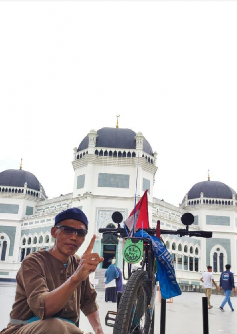 Tahja Umar Gunawan dengan sepedanya di halaman Masjid Baiturrahman Banda Aceh;