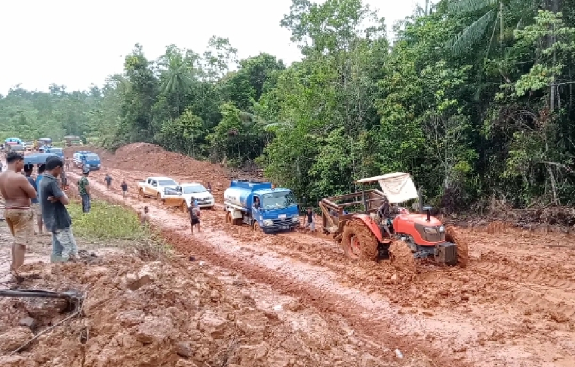 Kendaraan alat berat menderek truk tangki di jalan rusak jalur Merauke - Boven Digoel, Papua Selatan 