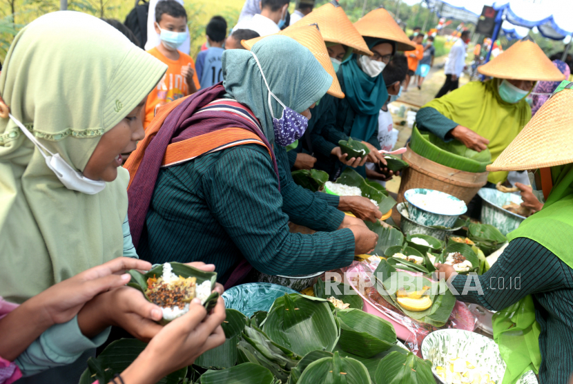 Warga membagikan nasi saat tradisi Wiwitan di Srandakan, Bantul, Yogyakarta, Rabu (19/5/2023). (Wihdan Hidayat/Republika)