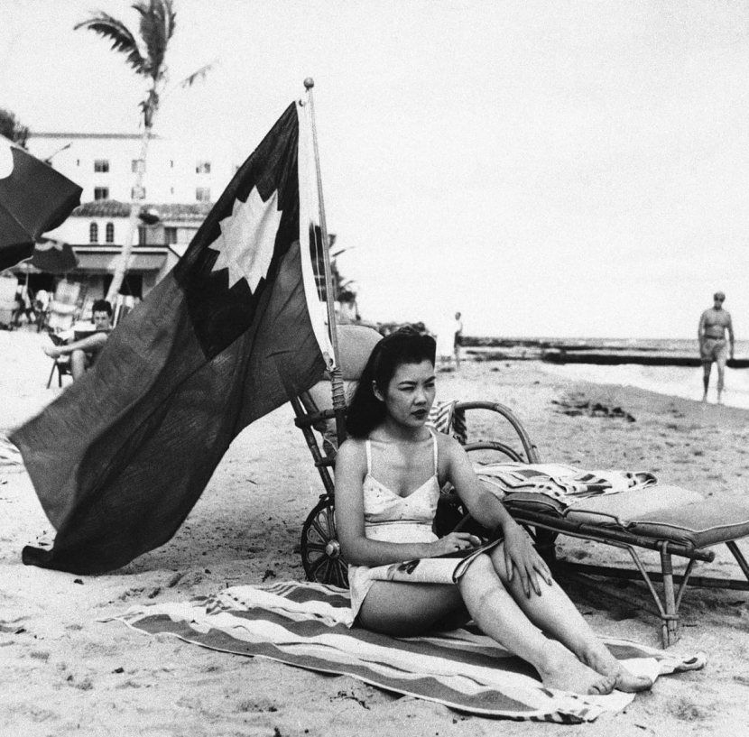 Ruth Lee berjemur di Pantai Miami sembari mengibarkan bendera kaum nasinonalis Tiongkok (kini bendera Taiwan).