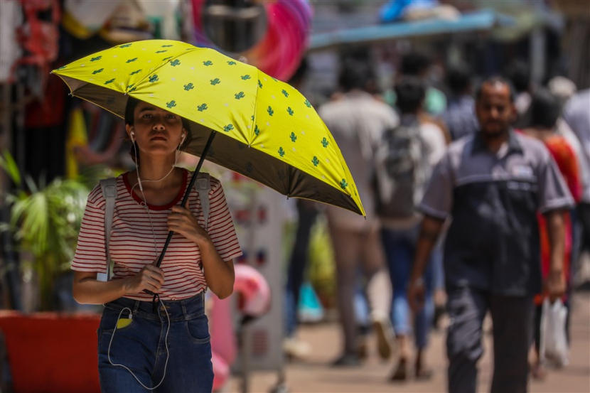 Seorang wanita berjalan dengan payung untuk melindungi diri dari gelombang panas di Mumbai, India, 17 April 2023. Asia Dikepung Suhu Setengah Mendidih, Warga Bisa Masak Telur di Bawah Matahari. Foto:  EPA-EFE/DIVYAKANT SOLANKI