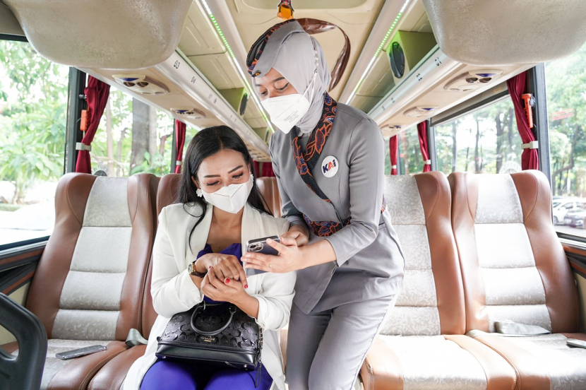 Pramugari PT Kereta Api Indonesia memberikan penjelasan kepada penumpang tentang Fitur E-Moda KAI Access di dalam bus Perum Damri. (Foto: Dok. PT KAI)