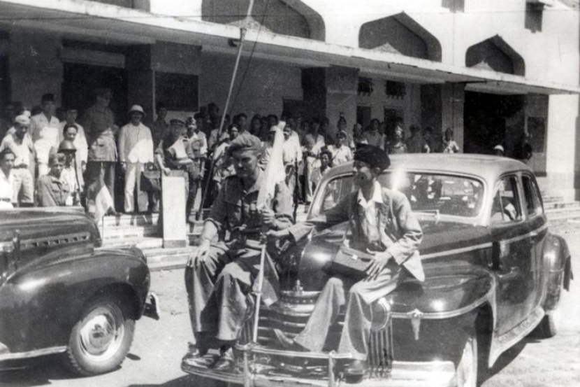 BrigJen Mallaby memegang bendera putih dan Residen Sudirman duduk di muka mobil keliling kota Surabaya menjelang pecahnya Pertempuran 10 November 1945.