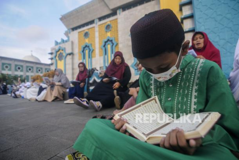 Sejumlah umat Islam membaca Alquran sambil menunggu waktu berbuka puasa di depan Masjid Raya Jakarta Islamic Center, Jakarta, Senin (18/4/2022). Foto: Republika/Putra M. Akbar