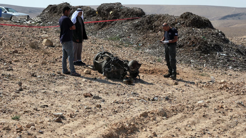 Seorang petugas polisi dan warga memeriksa sisa-sisa pendorong roket yang, menurut otoritas Israel, melukai parah seorang gadis berusia 7 tahun, setelah Iran meluncurkan drone dan rudal ke arah Israel, dekat Arad, Israel, pada 14 April 2024. Foto : Reuters