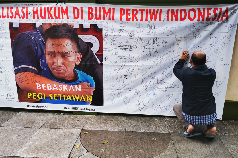 Warga yang melintas menulisi spanduk dan karangan bunga berisi dukungan bagi Pegi Setiawan di depan kantor PN Bandung, Jl Martadinata, Bandung, Senin (8/7/2024).