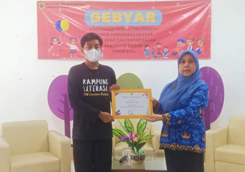 Eko Sri Haryanti SP dari DAP Kabupaten Bogor (kanan) menyerahkan Penghargaan Kampung Literasi yang diterima M Fadhil (Relawan TBM Lentera Pustaka) di Aula Perpustakaan Kabupaten Bogor hari ini, Jumat (28/10/2022).  (Foto: Dok TBM Lentera Pustaka)