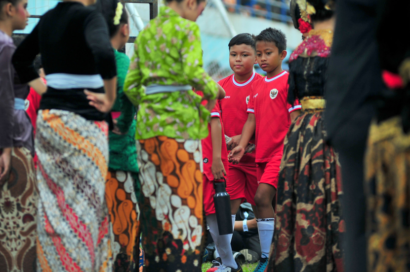 Dua anak pesepakbola dari SSB melintasi penari Kipas jelang upacara persemian Turnamen Piala Presiden 2024 di Stadion Si Jalak Harupat, Soreang, Kabupaten Bandung, Jumat (19/7/2024). (Foto: Yogi Ardhi/Republika Network) Nikon D3, Nikkor 300/2,8 ED MF