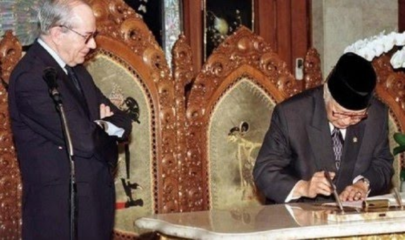 Presiden Soeharto menandatangi perjanjian dengan IMF pada 1998. Michel Camdessus terlihat memandanginya dengan bersedekap. (AP Photo)