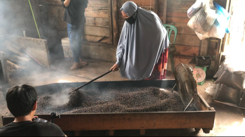 Kusniati tengah bekerja menyangrai kopi secara tradisional.