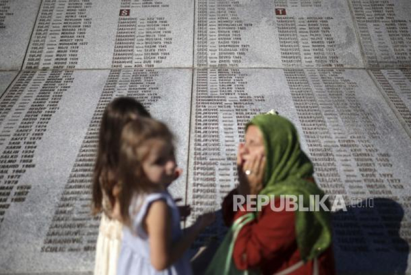  Seorang wanita muslim Bosnia berdoa di sebelah monumen dengan nama-nama mereka yang tewas dalam<a href=