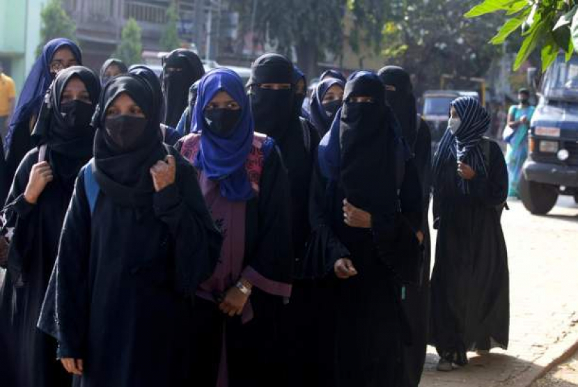 Mahasiswi yang dilarang memasuki kelas mereka karena berhijab, berjalan menuju kampus mereka di Udupi, India, Jumat (4/2). (Bangalore News Photos via AP)         