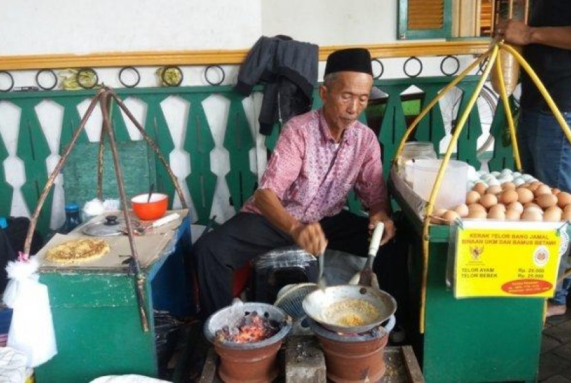 Penjual kerak telor dengan memakai gerobak. Kerak telor dibuat menggunakan beras ketan, telur ayam atau bebek, dan taburan serundeng kelapa dan bawang goreng di atasnya. Foto: Republika