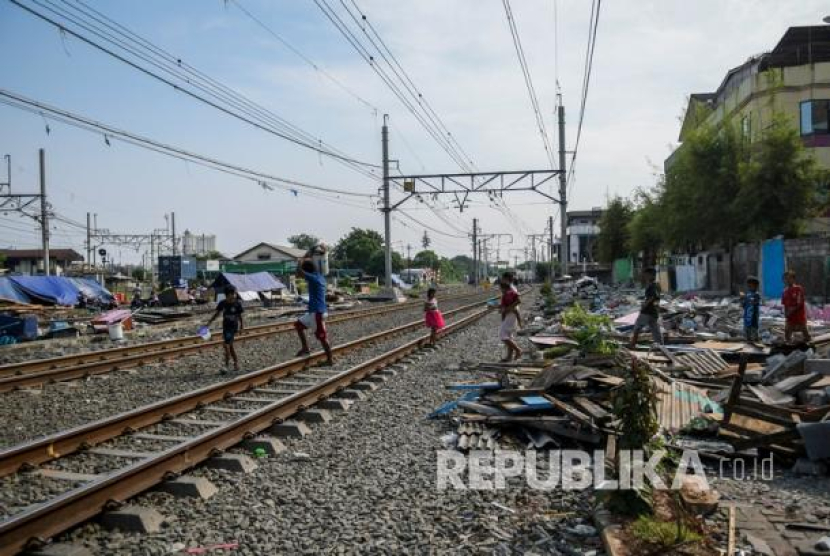 Warga terdampak penggusuran berjalan melintasi rel kereta api di dekat tenda sementara di Kampung Muka, Ancol, Jakarta, Sabtu (18/7/2020). (Antara/Galih Pradipta)