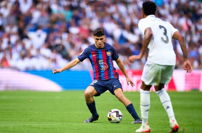 Gelandang Barcelona, Pedri (kiri), mengenakan jersey berlogokan burung hantu Drake saat menghadapi Real Madrid di laga pekan kesembilan La Liga Spanyol di Stadion Santiago Bernabeu, Madrid, pada Ahad (16/10/2022). (Twitter/@FCBarcelona)