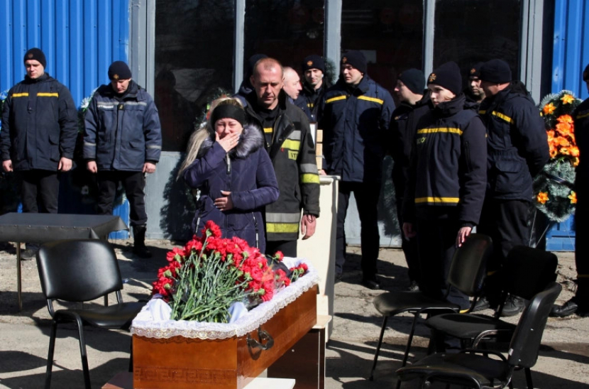 Istri petugas pemadam kebakaran yang telah meninggal Oleksandr Podilsky bereaksi selama upacara perpisahannya, ketika invasi Rusia ke Ukraina berlanjut, di Kharkiv, Ukraina [Oleksandr Lapshyn/Reuters]