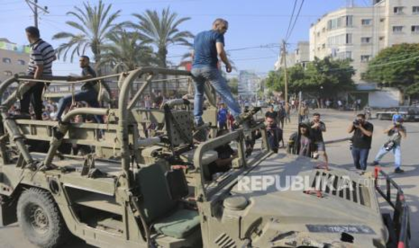 Warga Palestina menaiki kendaraan militer tentara pendudukan Israel yang berhasil dilumpuhkan pejuang Hamas Palestina di dekat perbatasan Kota Gaza, Sabtu (7/10/2023) waktu setempat. (AP/Abed Abu Reash/Republika.co.id)