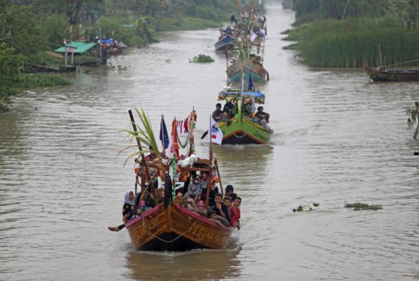 Warga menaiki perahu hias saat mengikuti Tradisi Nadran (pesta laut) di Sungai Cimanuk, Indramayu, Jawa Barat. (Foto: Antara)