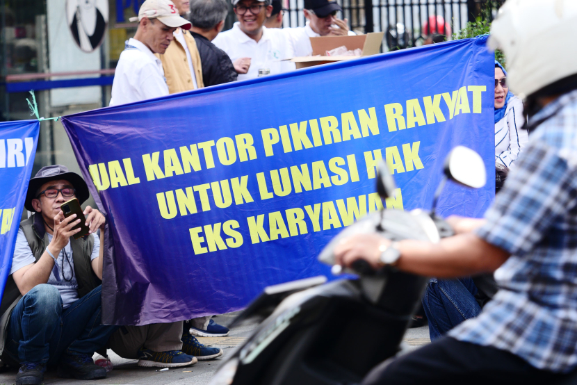 Eks Karyawan PR tampak tengah menggunakan ponsel di sela unjukrasa di depan halaman kantor redasi Pikiran Rakyat di Jalan Asia Afrika, Kota Bandung, Jawa Barat, Kamis (2/5/2024).