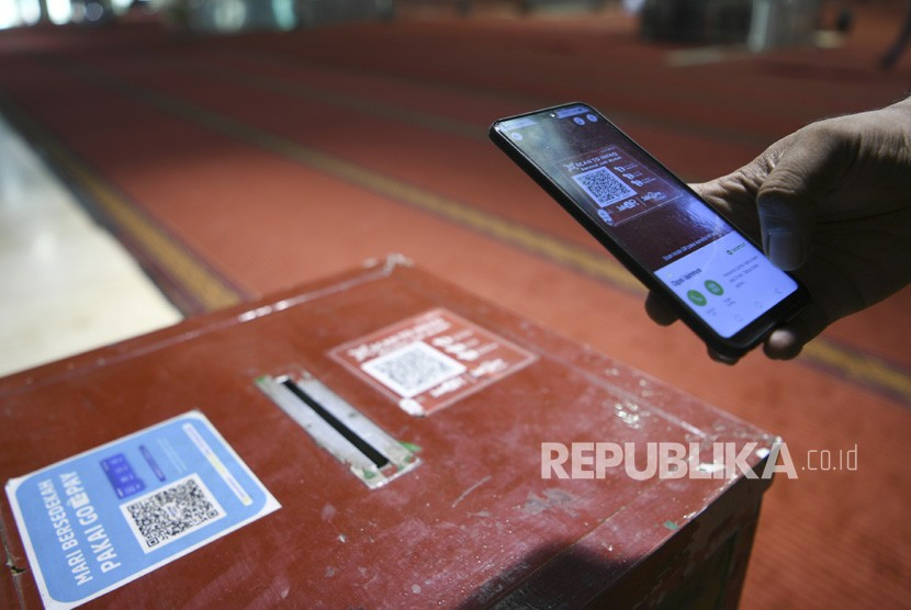 Seorang warga memindai barcode saat memberikan sedekah di Masjid Istiqlal, Jakarta. Foto: Antara/Wahyu Putro A