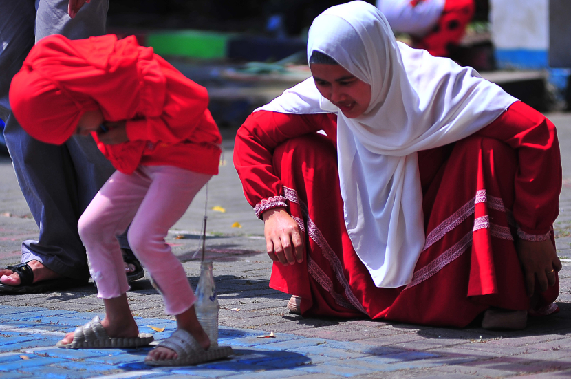 Seorang ibu menunggui anaknya yang tengah berlomba memasukkan pensil ke dalam botol  di kawasan Kompleks Pandanwangi, Margacinta, Bandung, Sabtu (17/8/2024). (Foto Yogi Ardhi/Republika Network) (Nikon D3, Nikkor 80-200/2.8 Gen III).