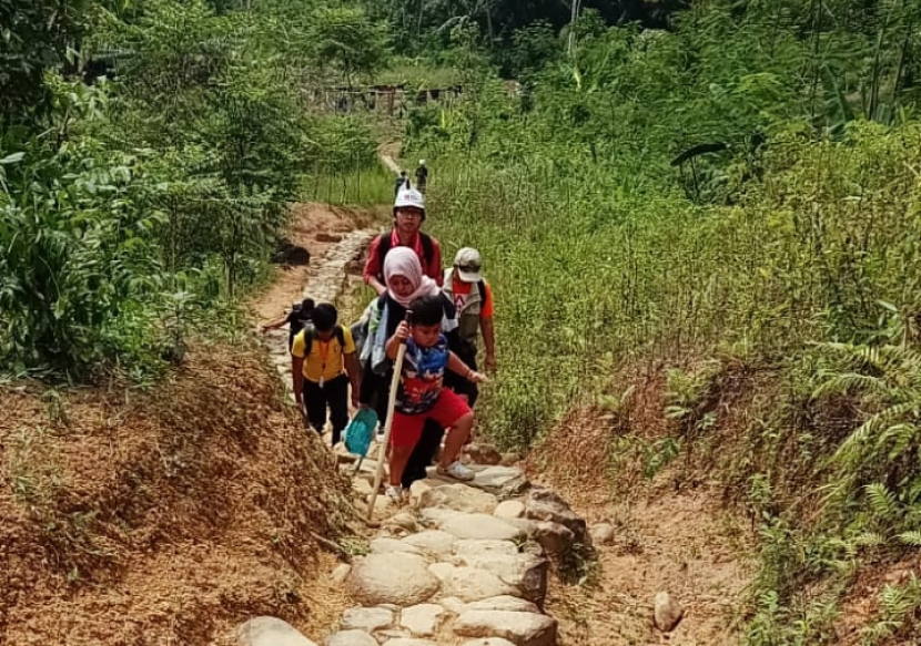 Syafathar menyusuri jalan menanjak ke Baduy Dalam. Ia peserta termuda, bocah berusia enam tahun.