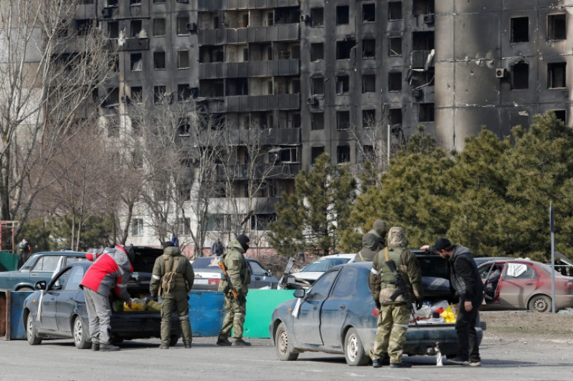 Anggota layanan pasukan pro-Rusia memeriksa mobil selama konflik Ukraina-Rusia di kota pelabuhan selatan yang terkepung Mariupol, Ukraina, 20 Maret 2022