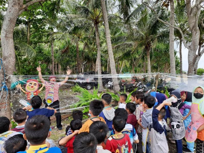 Kak Komang mengajari siswa SD Mutu Bawean melukis di plastik. (Foto: Mubarak/pwmu.co)