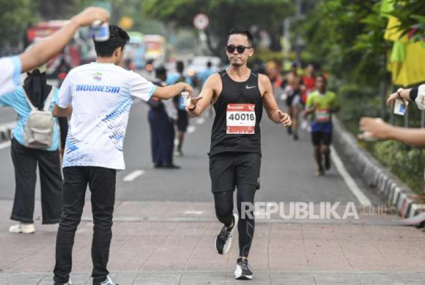 Seorang peserta mengambil air mineral saat mengikuti ajang Jakarta Marathon 2022 melintas di depan Lapangan Banteng, Jakarta, Ahad (16/10/2022). Foto: ANTARA/M Risyal Hidayat