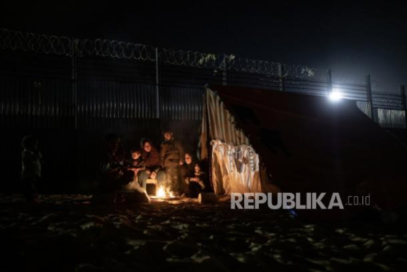 Keluarga Okasha yang mengungsi dari Gaza utara menghangatkan diri di depan tenda pengungsian mereka, dekat perbatasan Gaza-Mesir, Rafah, Selasa (27/2/2024). 