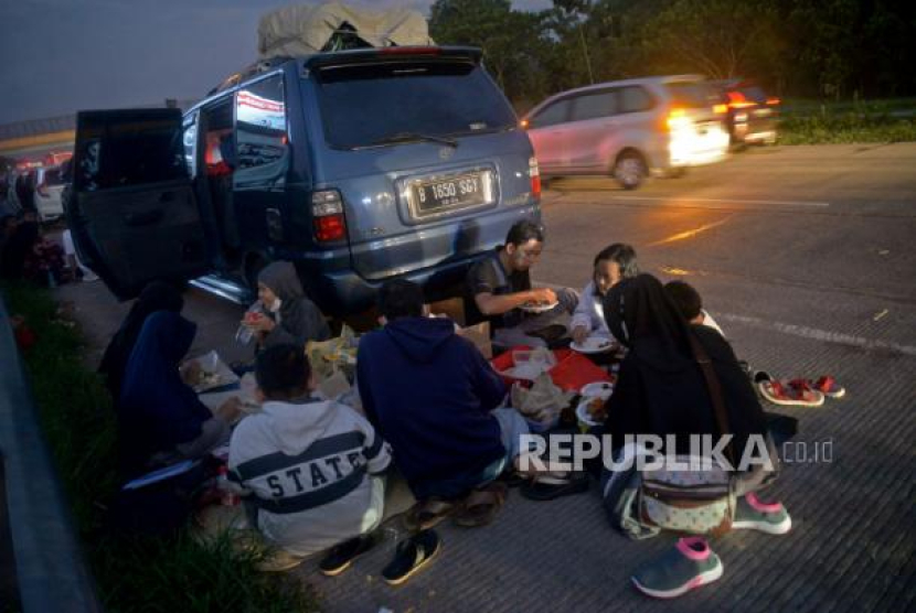 Sejumlah pemudik berbuka puasa sambil beristirahat di KM 102 ruas tol Cikopo-Palimanan, Subang, Jawa Barat, Kamis (28/4/2022). Padatnya sejumlah rest area di sepanjang jalan tol Trans Jawa membuat pemudik memanfaatkan bahu jalan untuk berbuka puasa dan istirahat sejenak. Berencana Mudik di Malam Hari? Ingat 5 Hal Ini Saat Berkendara. Foto: Republika/Prayogi