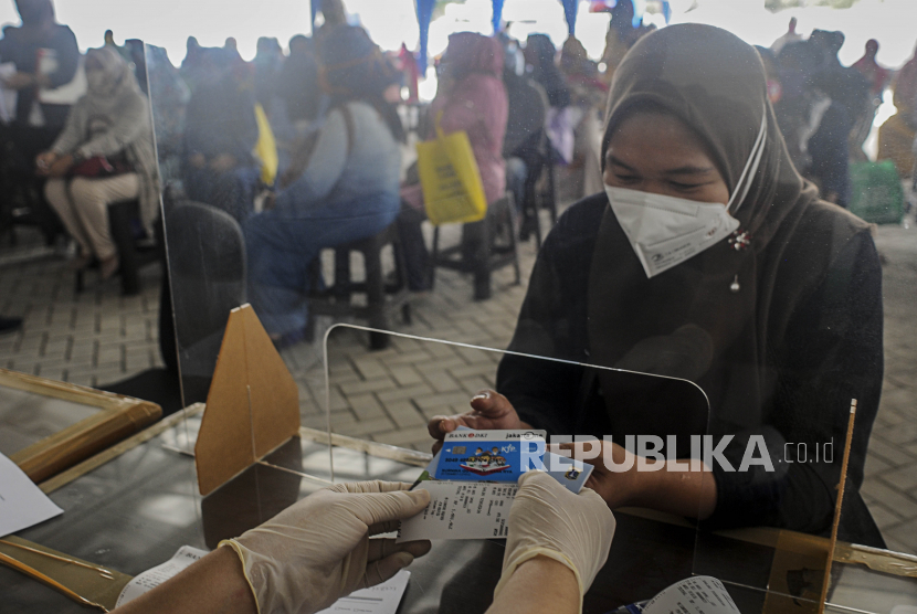 KJP Plus. Petugas memberikan kartu ATM Bank DKI dan buku rekening untuk orang tua dari anak penerima Kartu Jakarta Pintar (KJP) Plus.