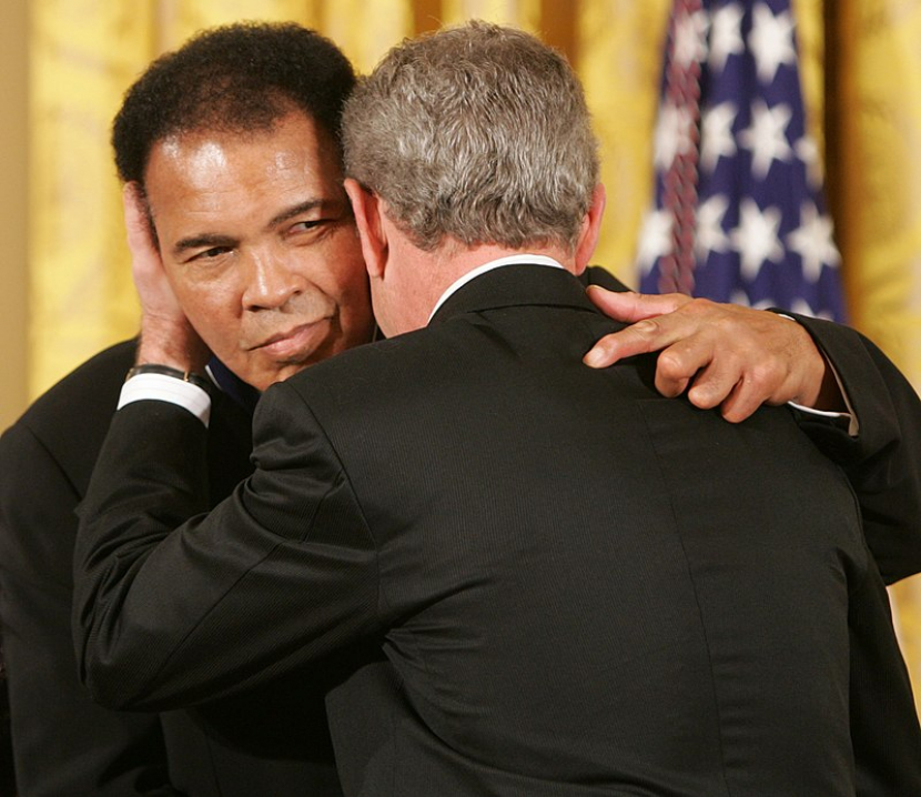 Presiden AS George W Bush (kanan) memeluk Muhammad Ali usai pemberian Presidential Medal of Freedom di Gedung Putih, 2005. (Gedung Putih/Wikimedia)
