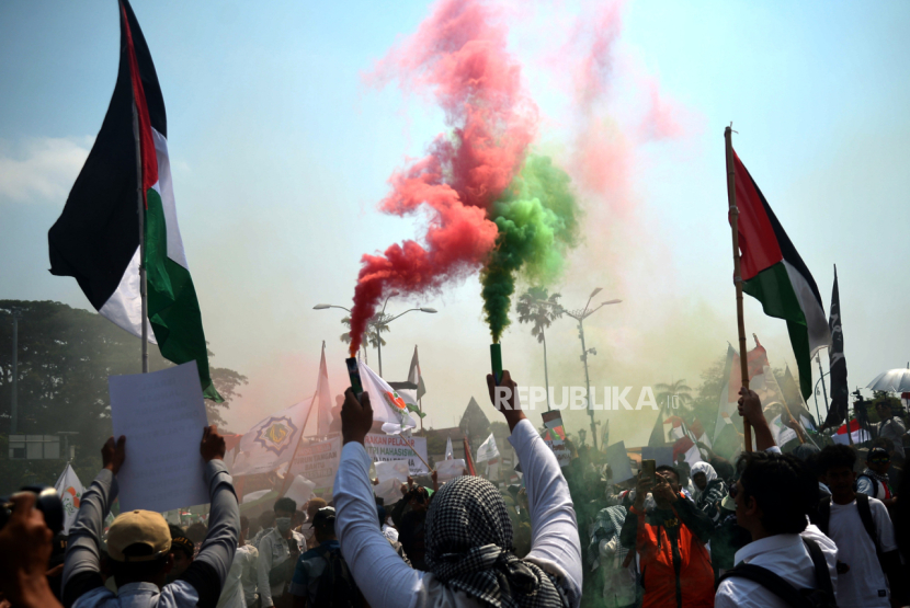Peserta menyalakan suar saat mengikuti aksi damai Indonesia Turun Tangan Bantu Palestina di Titik Nol Kilometer Yogyakarta, Sabtu (21/10/2023). (Republika/Wihdan Hidayat)