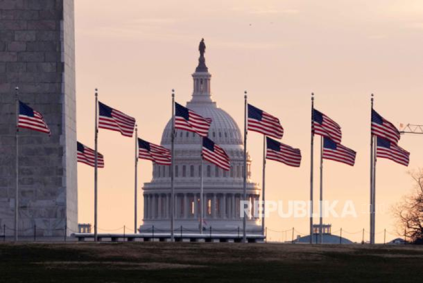 Gedung Capitol Amerika Serikat (AS) terlihat di belakang dasar Monumen Washington sekitar fajar di Washington, DC, AS (3/1/2024) di antara kibaran bendera Amerika Serikat. (dok. EPA-EFE/MICHAEL REYNOLDS)