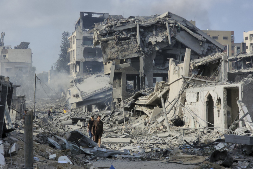 Warga Palestina berjalan melewati puing-puing bangunan yang hancur akibat serangan udara Israel di Kota Gaza pada Rabu, (11/10/2023) WIB. | AP Photo/Hassan Eslaiah