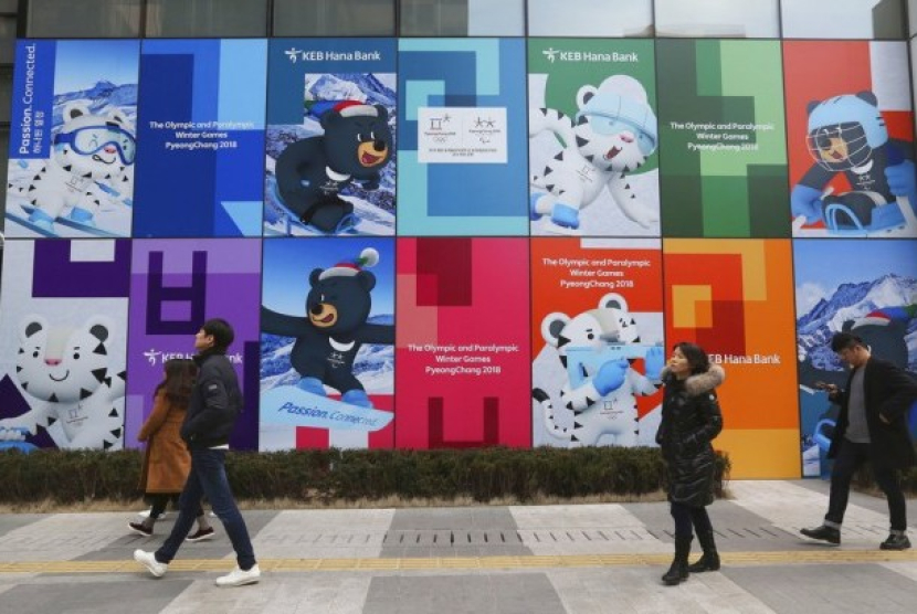 Warga berjalan melewati poster maskot Olimpiade Musim Dingin Pyeongchang 2018 di Seoul, Korea Selatan. Foto: AP Photo/Ahn Young-joon 