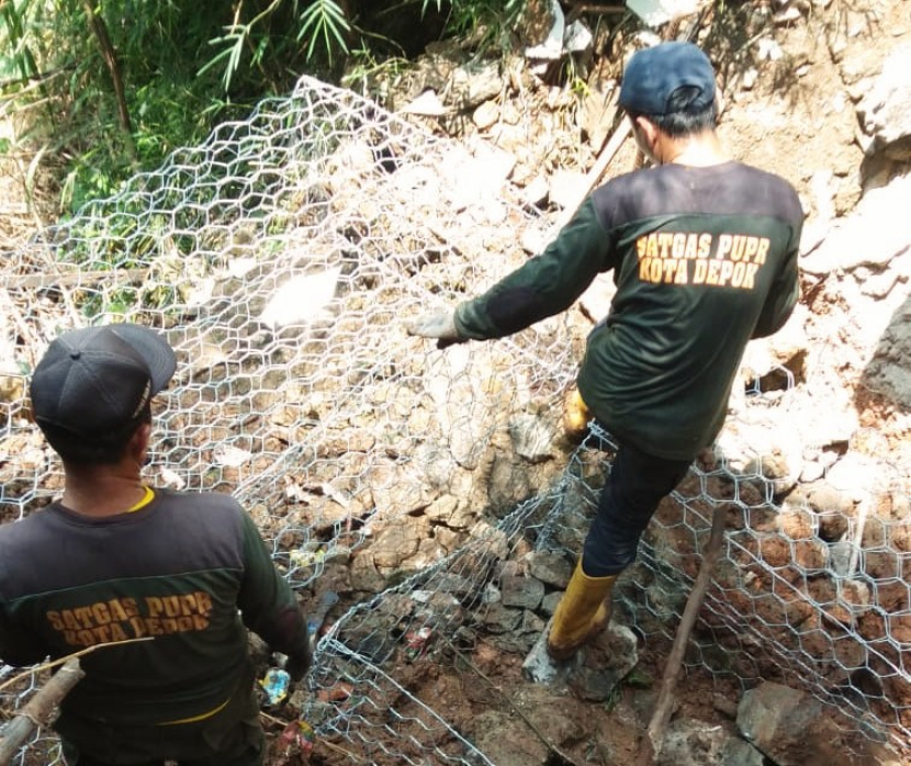 Petugas Satgas Dinas PUPR Depok sedang memasang bronjong di lokasi longsor di Perumahan BSI.