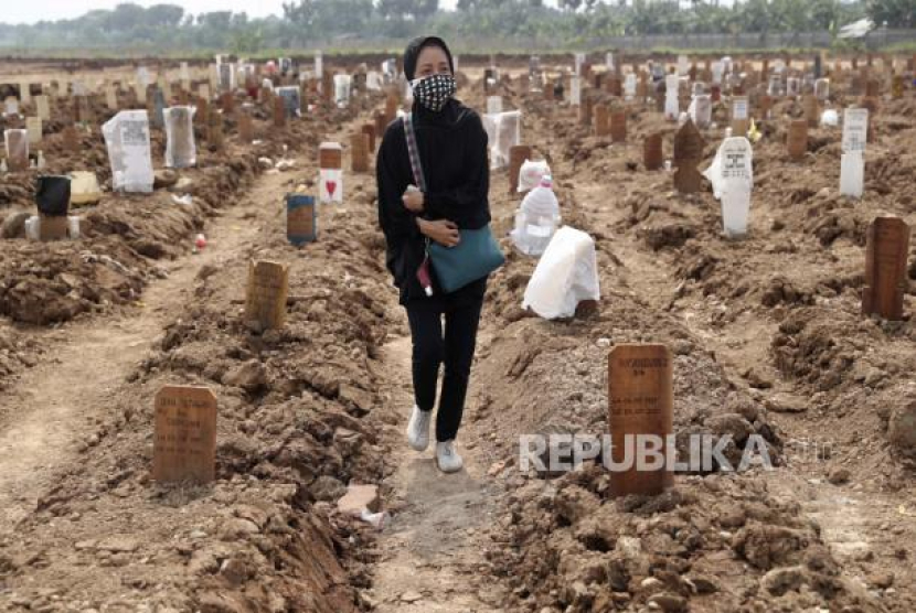 Seorang wanita berjalan di antara kuburan korban Covid-19 di Pemakaman Rorotan di Jakarta, Rabu, 7 Juli 2021. - (AP/Tatan Syuflana)